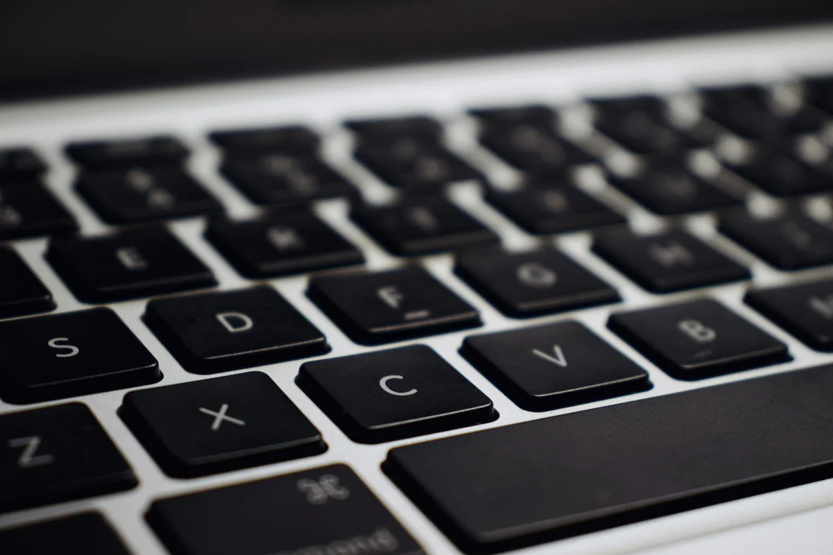 Close-up of a laptop keyboard with student notes in the background